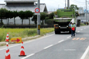 総社市でダンプカーの後進誘導を行う警備員